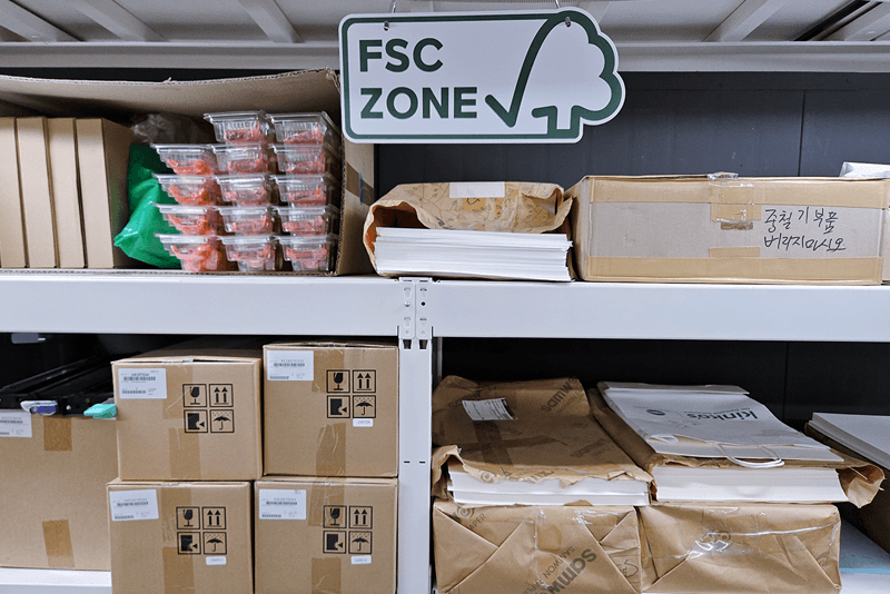 1_생산제작_16_킨코스 직원이 인쇄 공정 중 용지를 정렬하며 품질을 점검하는 장면, 인쇄물 접지 및 후가공 과정의 세밀한 관리 모습.png